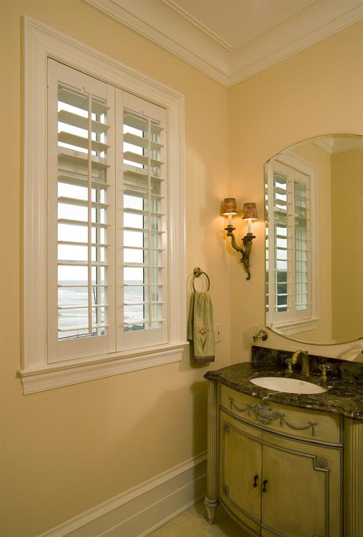 White shutters in a light bathroom looking out over ocean